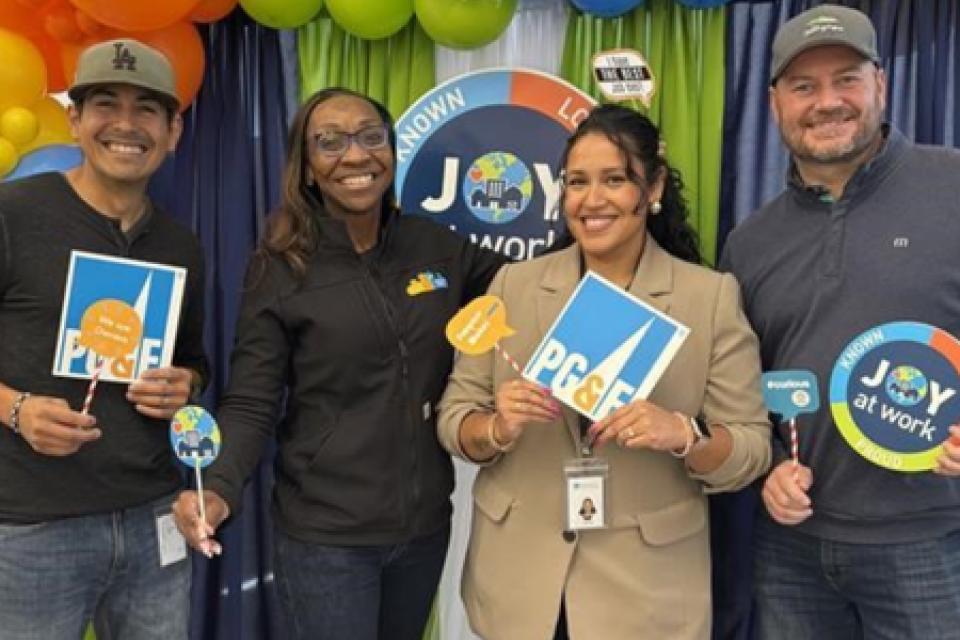 Verenice Andrade with three people, holding up PG&E signage in front a balloon display