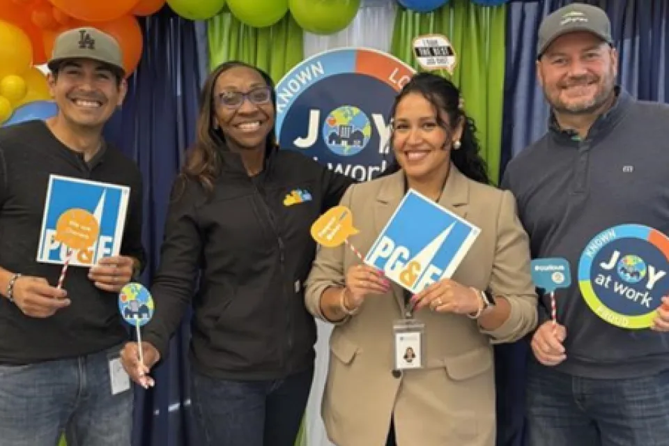 Verenice Andrade with three people, holding up PG&E signage in front a balloon display