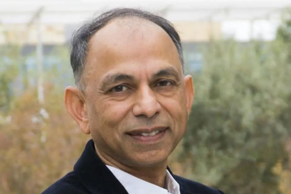 Hemant Bhargava wearing a dark blazer and white shirt, standing outdoors with greenery in the background.
