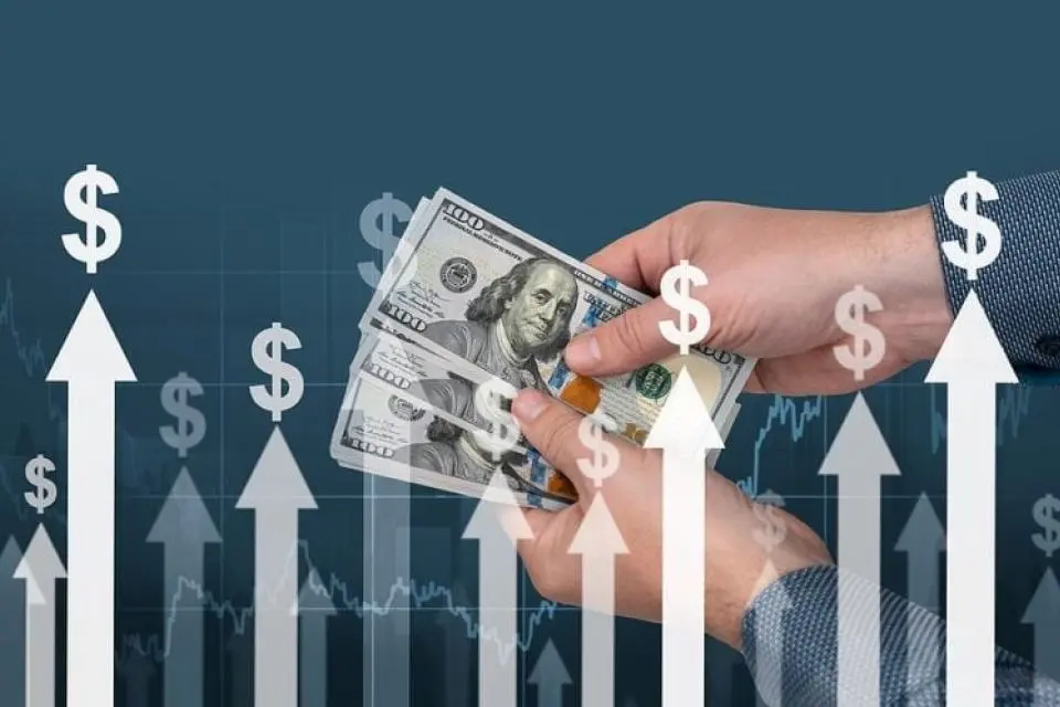 A person holds several US $100 bills, with upward-pointing white arrows and dollar signs symbolizing financial growth or rising profits.