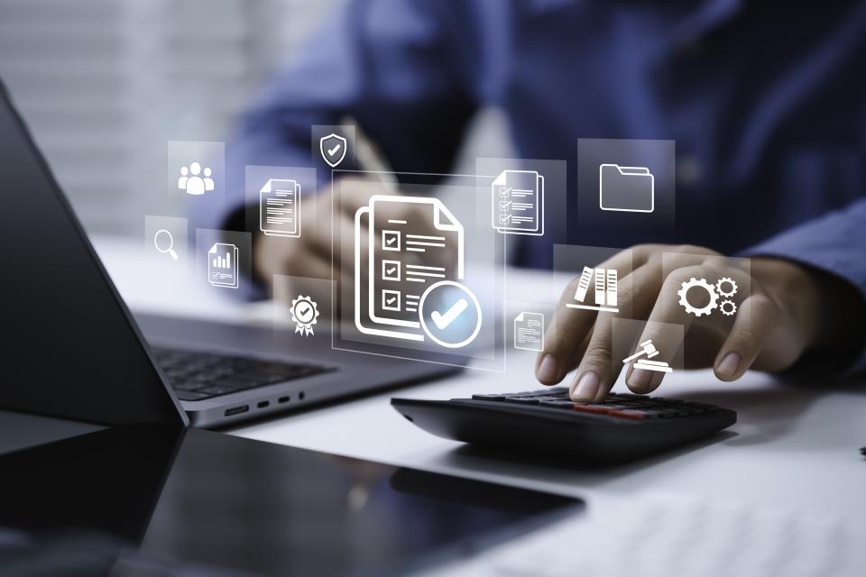 Person using a calculator and laptop at a desk, with digital icons for documents, analytics, and data management overlaid on the image.