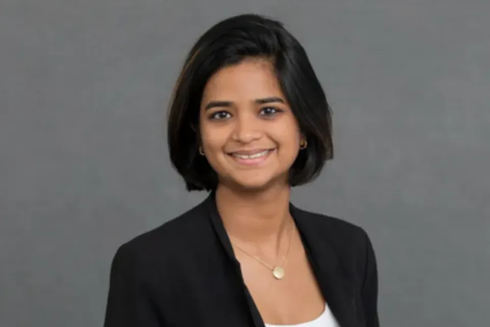 Headshot of a smiling woman with shoulder-length dark hair wearing a black blazer.