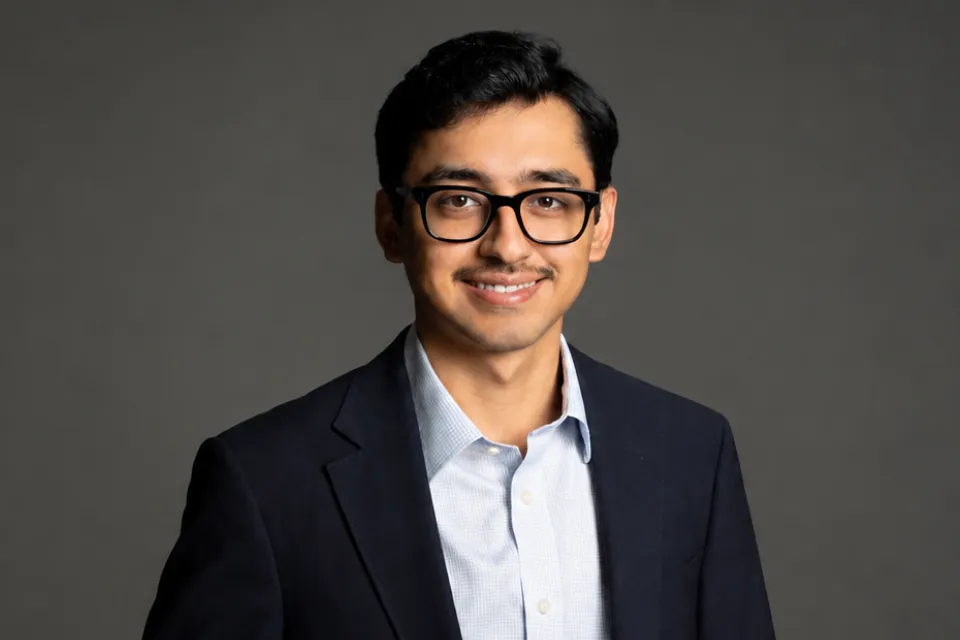 A man with a mustache and glasses wearing a suit jacket and dress shirt.