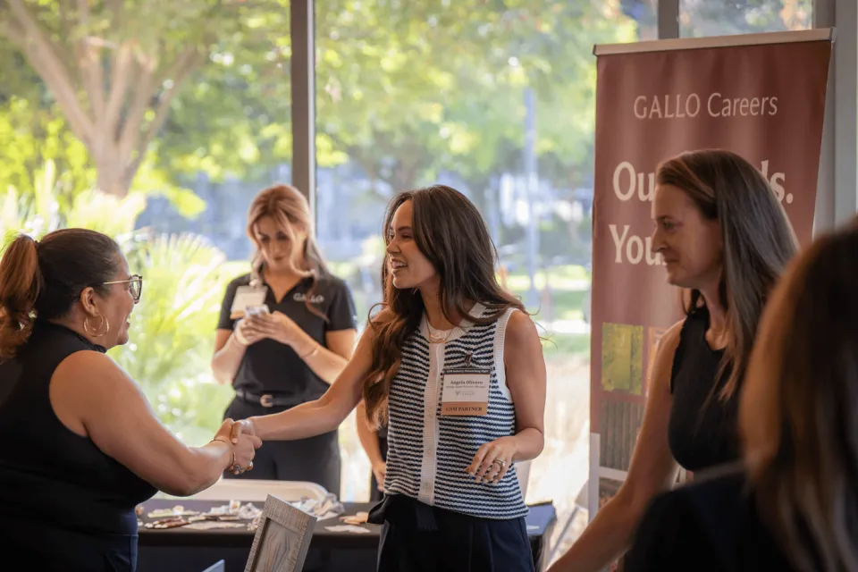 Two women shaking hands at a Gallo Careers job fair booth.